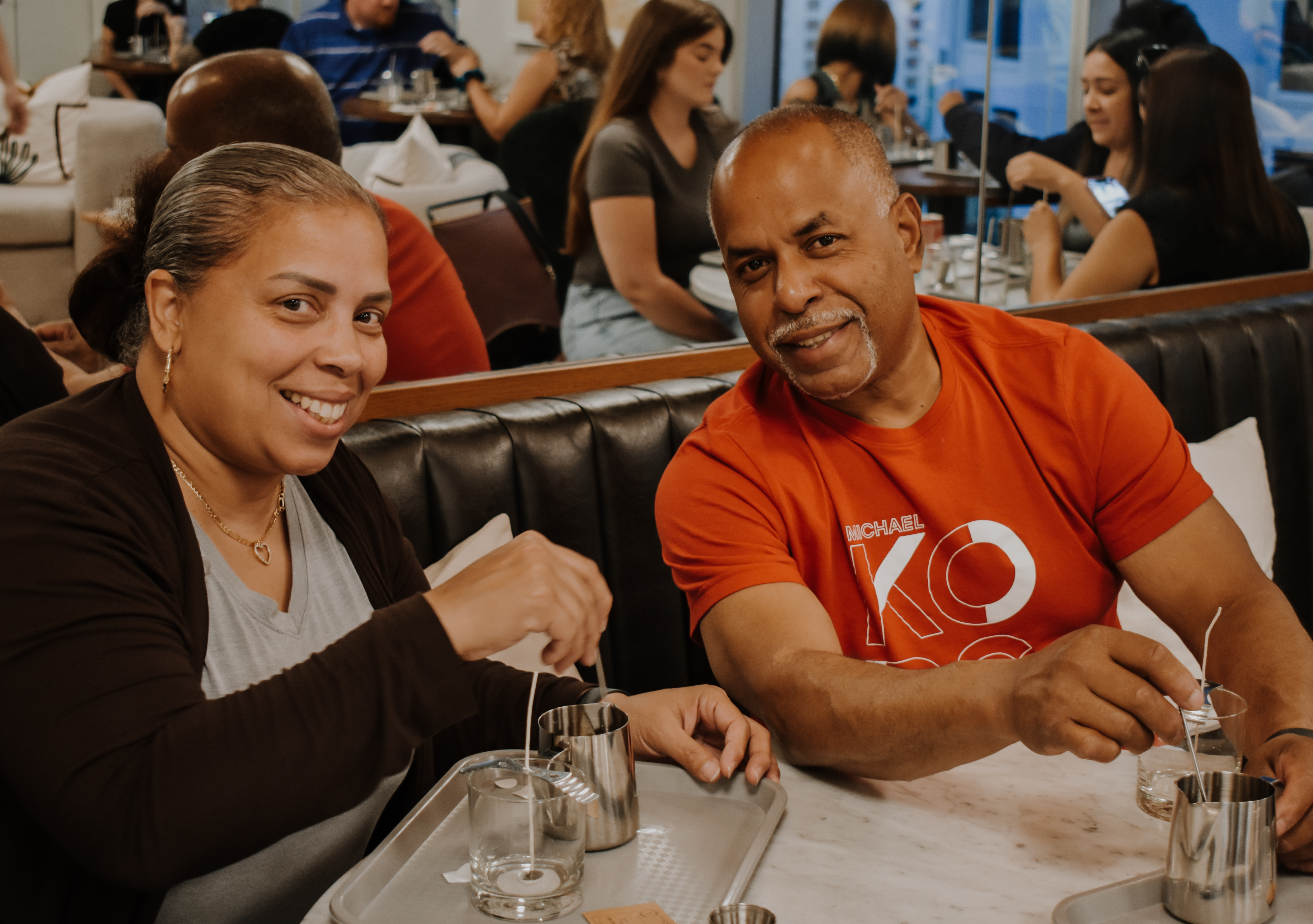 Guests smiling while making candles around a table